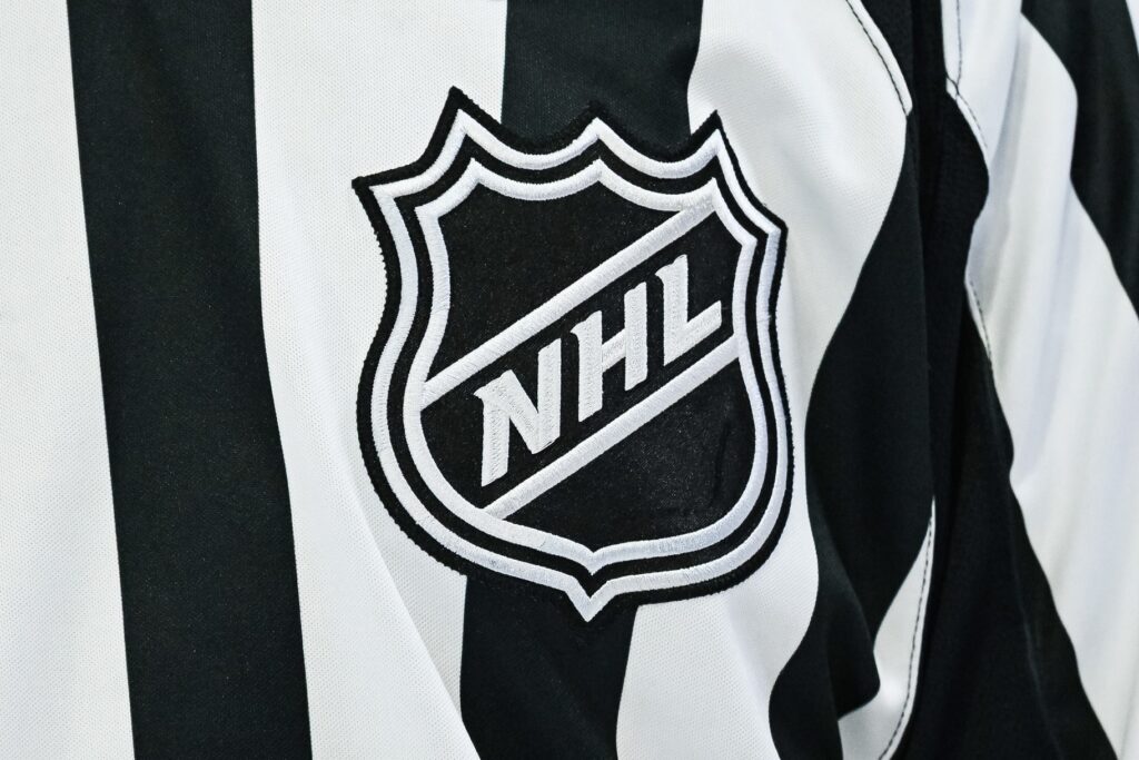 https://predictionpro.com/uncategorized/auto-draft Pictured: View of an NHL logo on a jersey worn by a linesman.